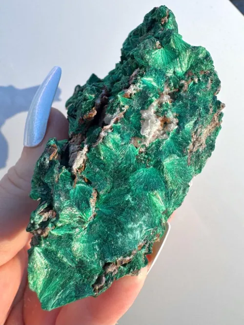 Close-up of a polished malachite cabochon surface showing intricate banding patterns, alongside a magnified image hinting at its fine internal structure and porosity